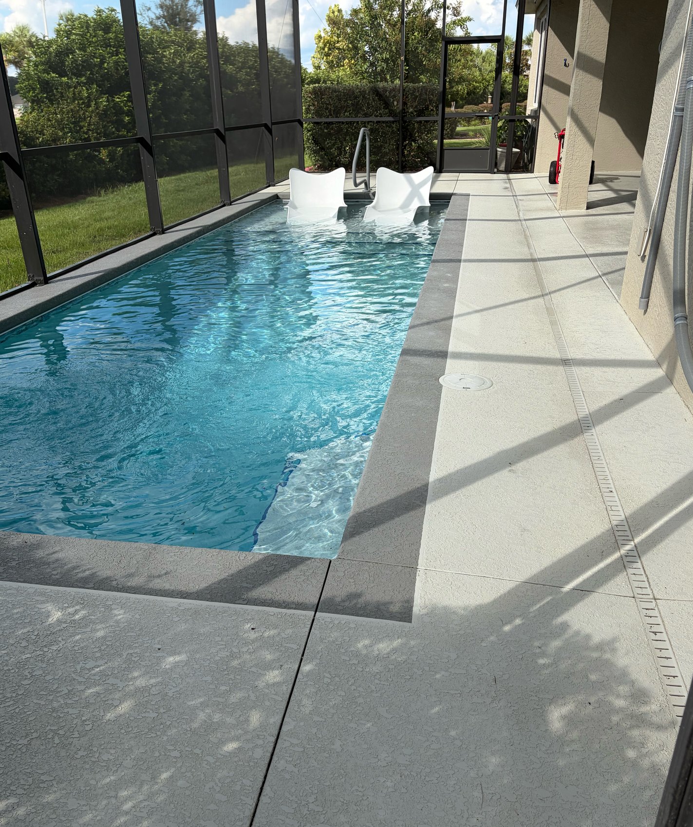 Cool deck after cleaning — wet textured pool deck beside clear pool