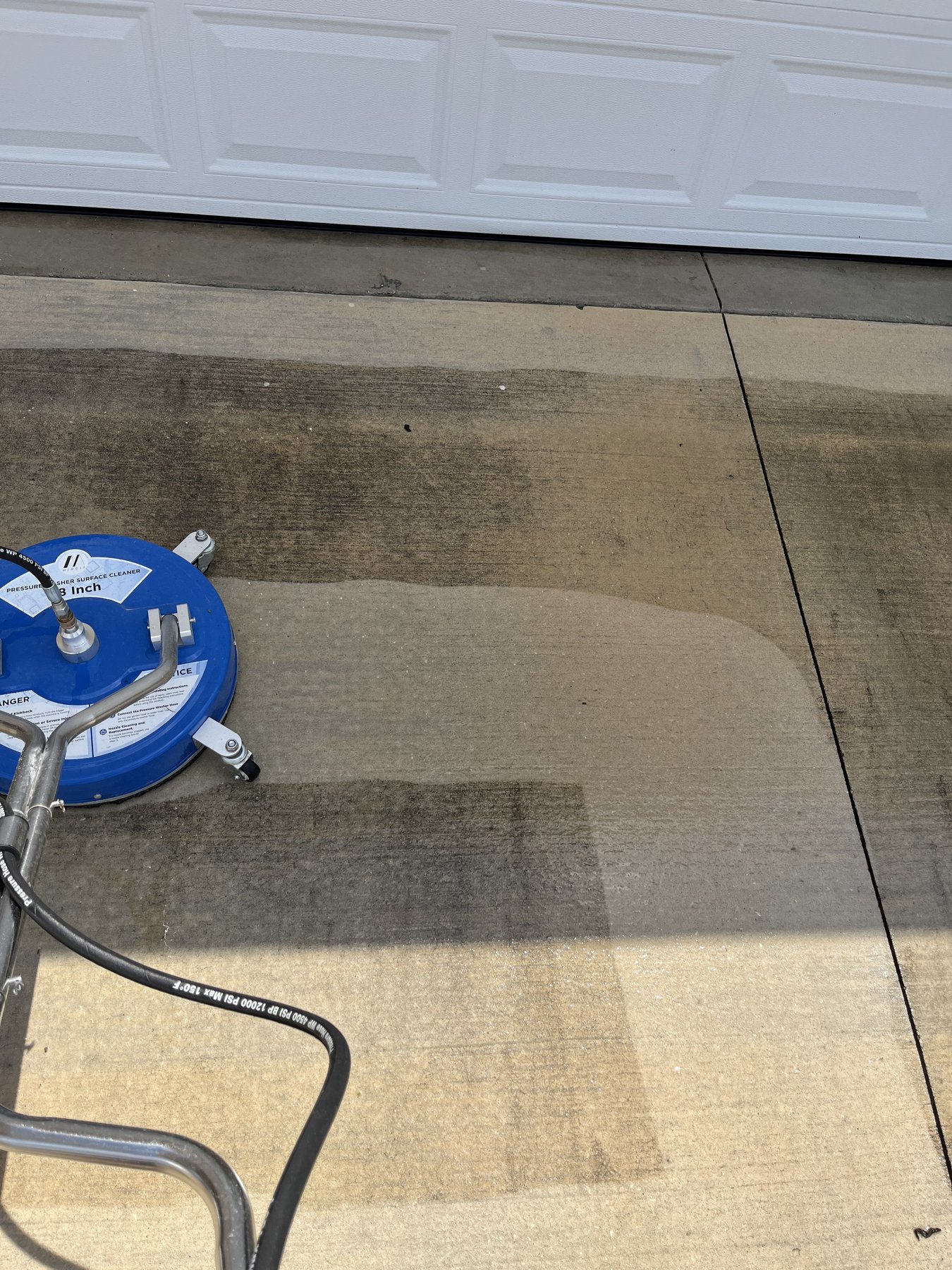 Garage driveway during surface cleaning — clean stripe versus dirty