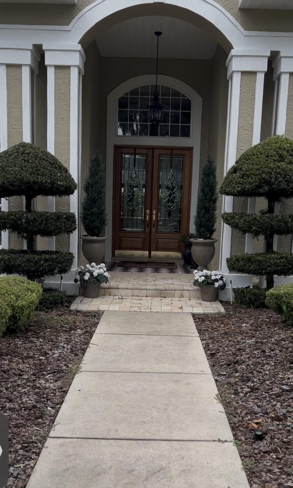 Front entry walkway before — mottled dirty concrete leading to arched double doors