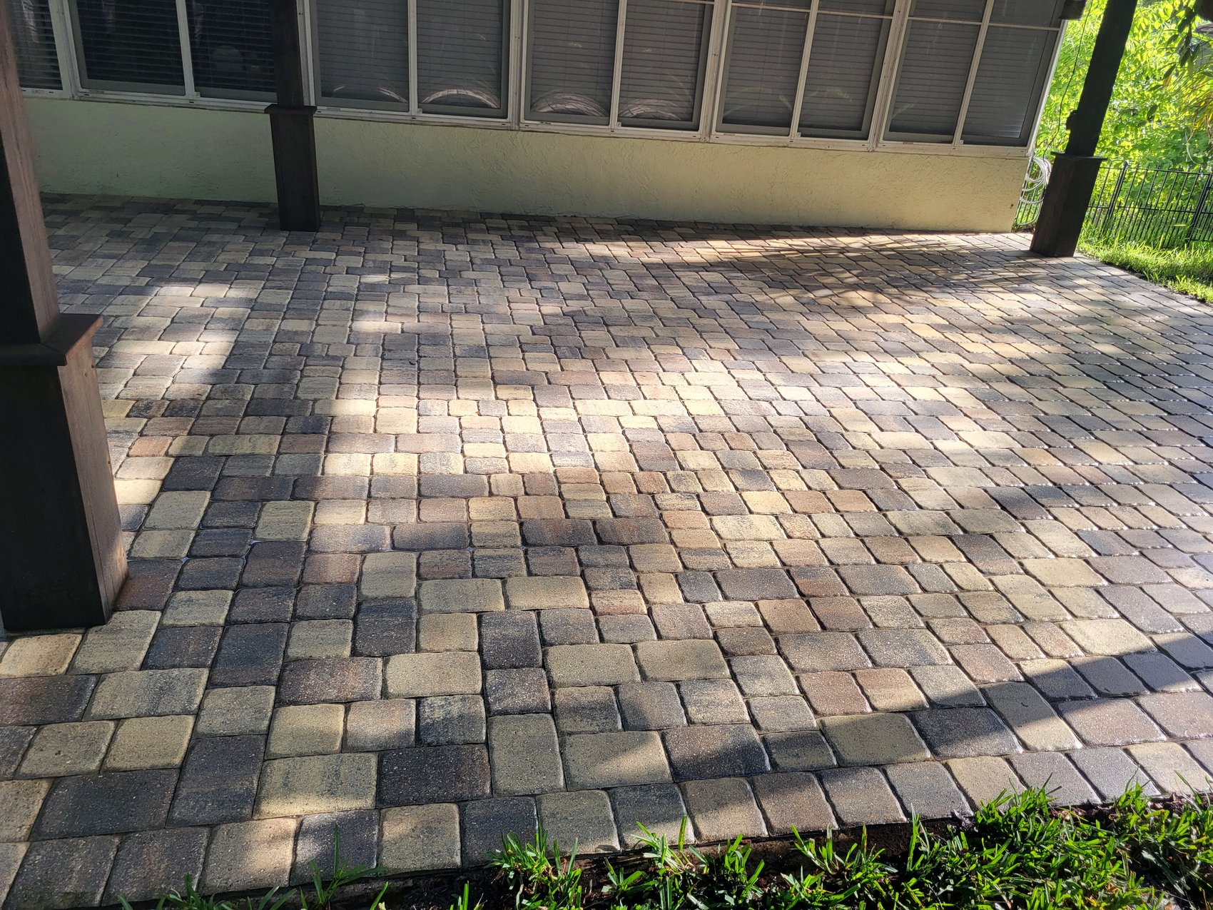 Paver patio after — cleaned multi-tone pavers with light joint sand under pergola