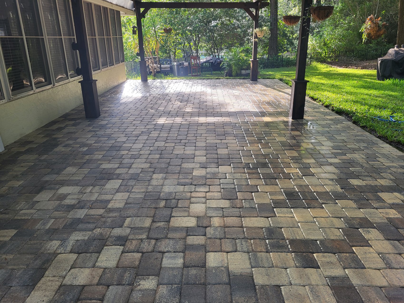Wide paver patio after — cleaned pavers, hanging baskets, lawn edge