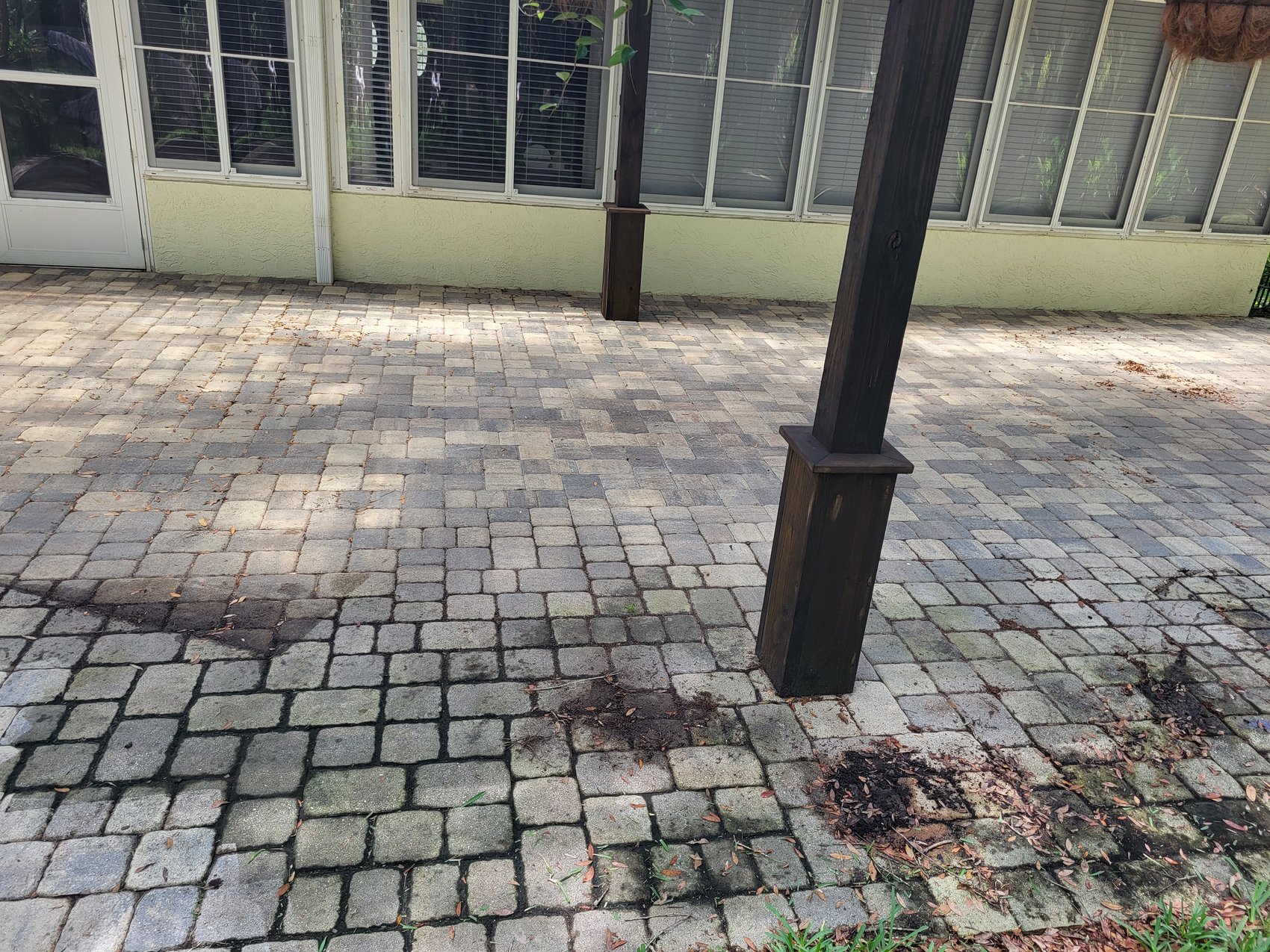 Paver patio before — dirty interlocking pavers and dark joints under pergola