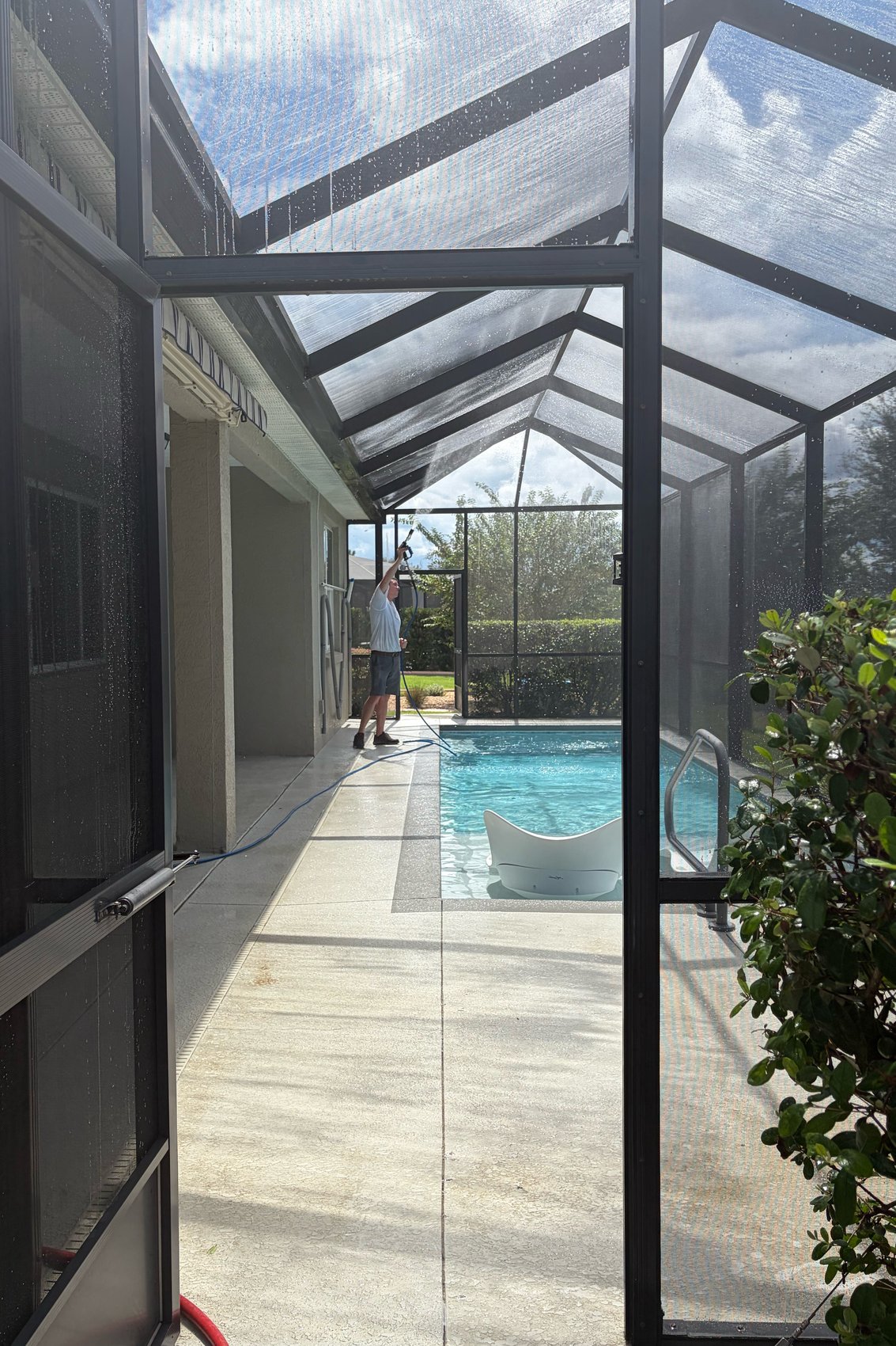 Screen enclosure wash in progress — soft wash wand on pool cage