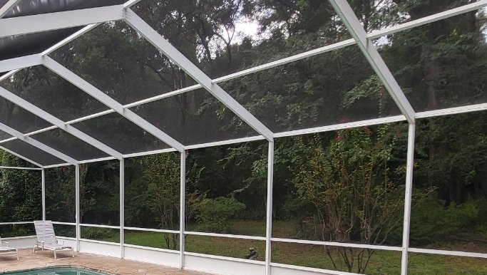 Clean screen enclosure after — white frame looking toward woods