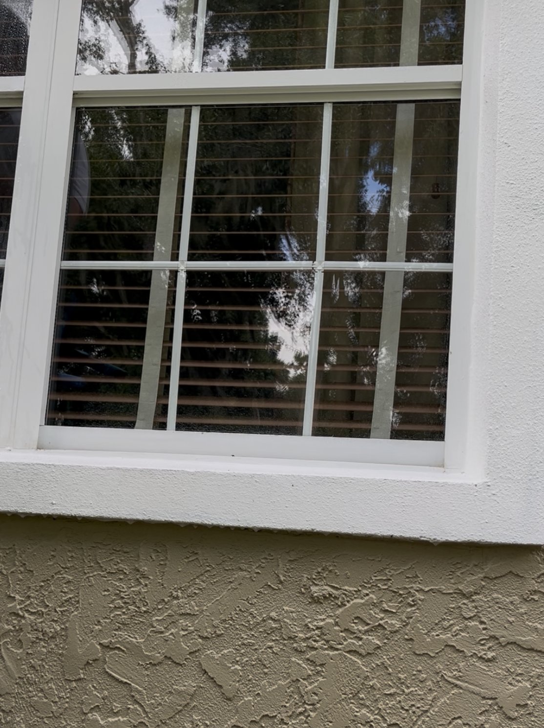 Multi-pane window after cleaning — clear glass on tan stucco