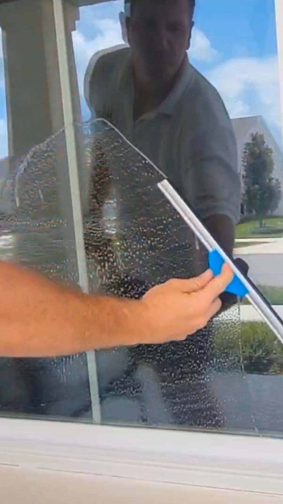 Close-up squeegee clearing soapy glass mid-stroke