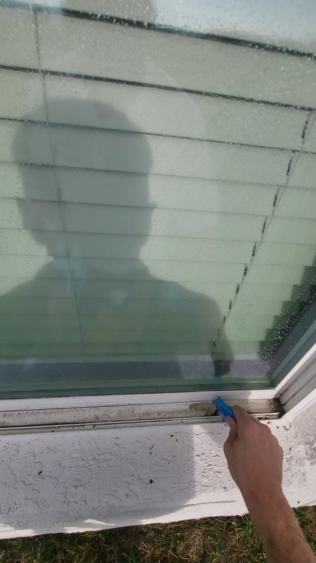 Window track scrub in progress on teal stucco home