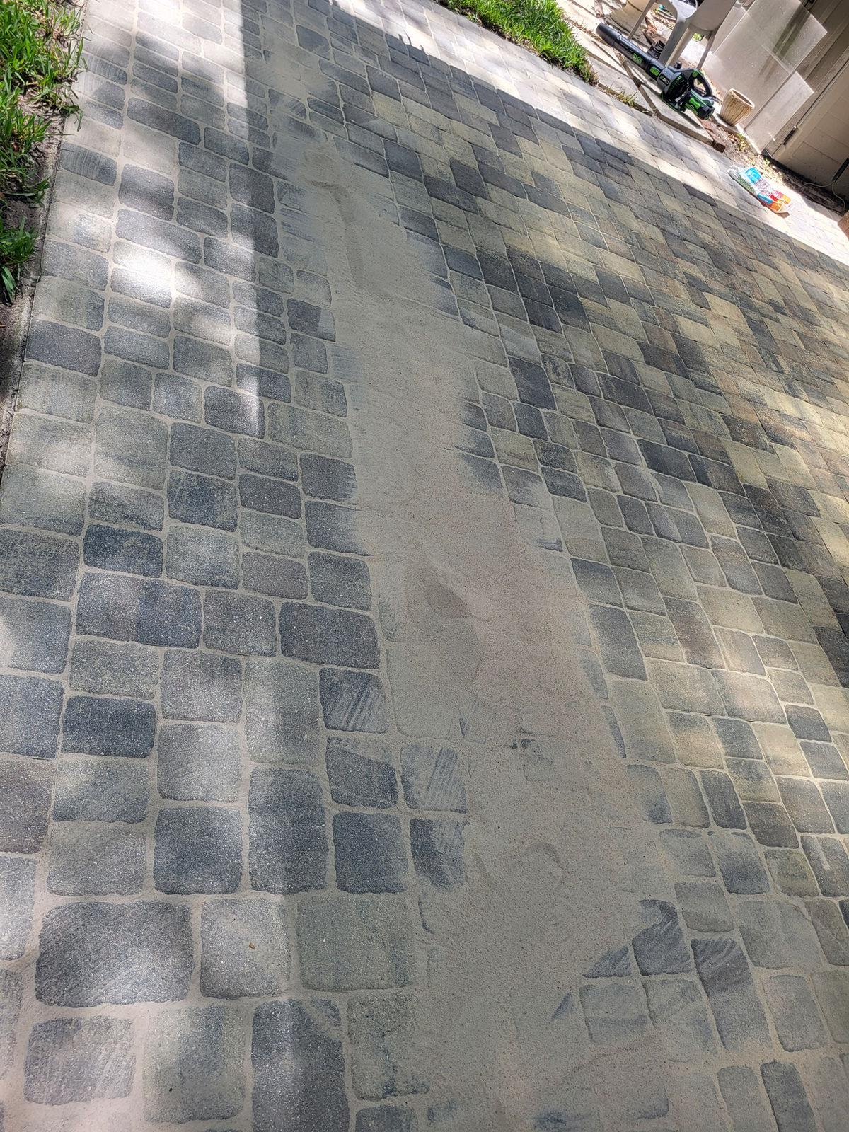 Paver restoration — joint sand after cleaning (sand swept into cobblestone-style paver joints)
